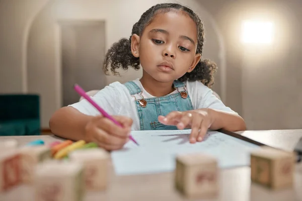 Girl, homework and writing on paper, learning and homeschool with math, education and knowledge at table in home. Latino child or student in brazil with concentration, school work and study in house.