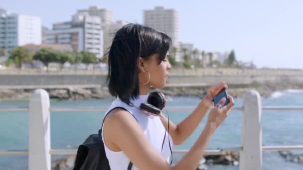 場所の更新のためのスマートフォン上のビーチ写真と旅行の女性 自然健康のソーシャルメディアの投稿とブログ ケープタウンの海や海のプロフィール写真のための電話を使用して幸せな女性や女の子 — ストック動画