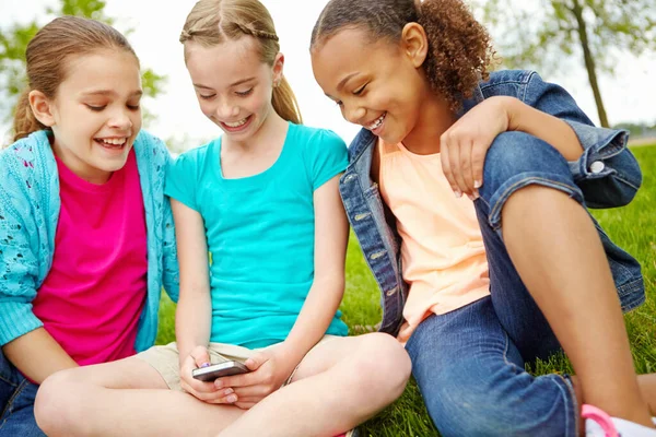 Ive got a text. Three little girls spending time together and sharing a smartphone while outdoors