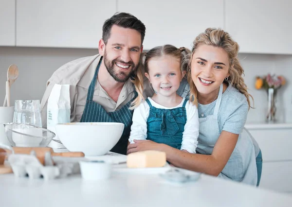 Portrait of happy parents hugging their daughter.Mother and father baking with their daughter. Caucasian family bonding in the kitchen. Smiling parents embracing their little girl