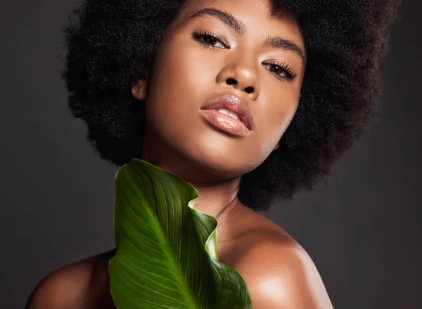Whos ready for healthy looking skin. an attractive young woman covered with a plant against a studio background