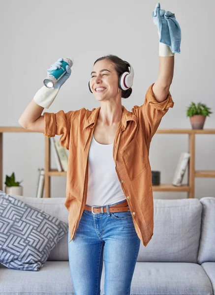 Happy, dance or woman cleaning with music streaming on headphones to relax to radio audio at home. Smile, wellness, or excited cleaner dancing with cloth or spray bottle to wipe dirty dusty bacteria.