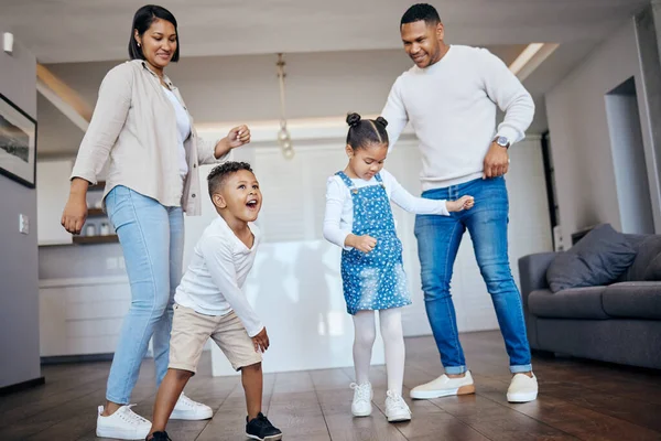 Mixed race family having fun and dancing in the living room at home. Little boy and girl having a fun day at home with their parents. Having dance battle with fun parents.