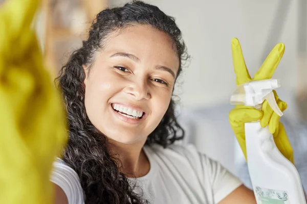 Happy, cleaning or woman taking a selfie with peace hand gesture with liquid soap in spray bottle for dust or bacteria. Cleaner or maid smiles with cleaning products, gloves or disinfection chemicals.