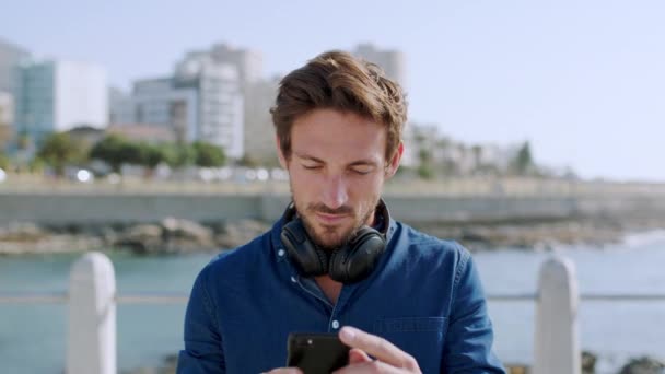 日当たりの良い散歩休憩にメッセージを入力しながら ビーチ思考でリラックスした 男と電話のソーシャルメディア ポルトガル スペインのモバイルとインターネットアプリ上の休暇の人のデジタル 5Gと通信 — ストック動画