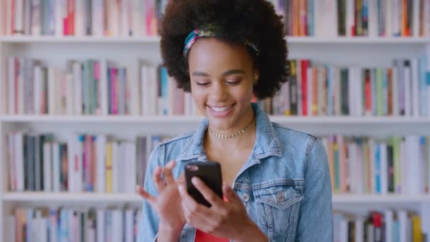 大学キャンパスの教育開発のための図書館で電話 ソーシャルメディア 黒人女性学生 勉強のための書店で女子学生との移動 コミュニケーション — ストック動画