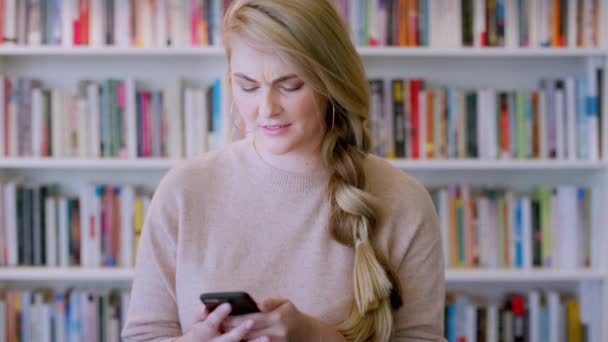 Biblioteka Nauczycielka Wyszukiwanie Telefoniczne Online Kobietą Wyglądającą Zdezorientowaną Podczas Czytania — Wideo stockowe