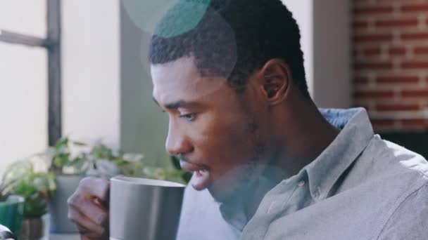 コーヒー 朝の黒人男性は デジタル新聞記事 ウェブサイトのブログやオンラインのソーシャルメディアの話を読んで Ui画面 お茶を飲むとニューヨークのアパートでスマートフォンでアフリカ人をリラックス — ストック動画