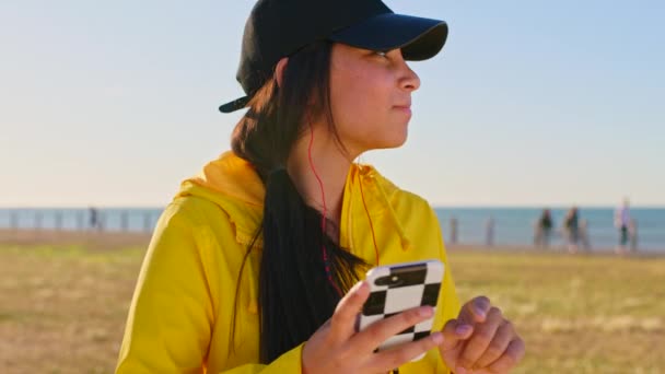 带着智能手机的少女 公园里带着带着音乐和自由的耳机 脸和自然 社交媒体的滚动和交流 收音机 一代青少年和科技 迈阿密海滩景观 — 图库视频影像