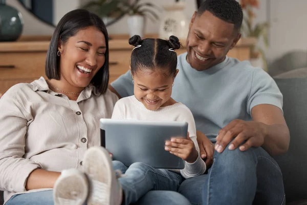 A happy mixed race family of three relaxing on the sofa at home. Loving black family being affectionate on the sofa while using a digital tablet and streaming. Young couple bonding with their daughte.