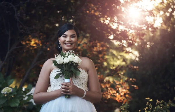 I feel like a princess today. a young bride posing outside with her bouquet