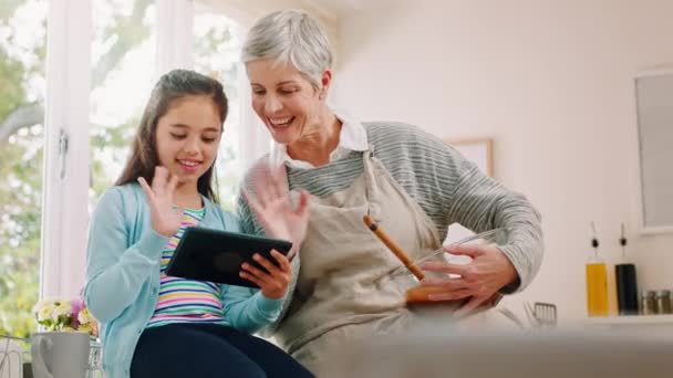 タブレットビデオ通話 波と技術に祖母 家庭料理や通信を持つ少女 会話と子供吹いてキスとともにシニア女性ベーキングとともにA Hello Tech — ストック動画
