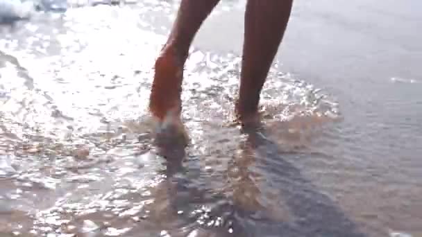 夏休み または休日の旅行のためのビーチでの足 足は屋外でリラックスします ぬれた海岸を裸足で歩き つま先の間で海を飛び散ったり楽しんだりする人 — ストック動画