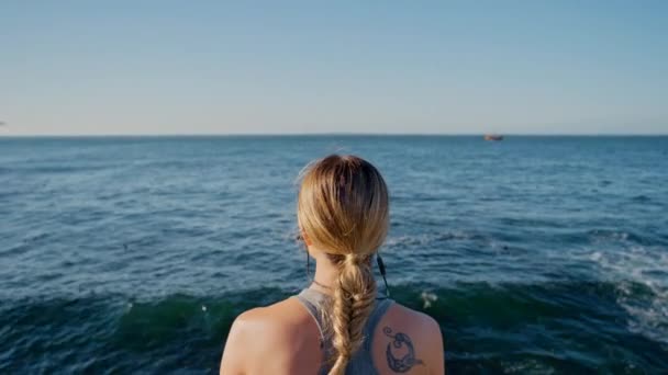 海で音楽とリラックスし フィットネスや女性 コスタリカでの心臓発作のための自然トレーニングやポッドキャスト ビーチでのワークアウト中にオーディオ付きの女の子の海 ワークアウトや背中 — ストック動画