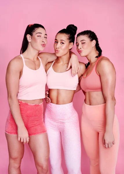 スポーティとお菓子 スタジオポートレートのピンクの背景に一緒に立ってスポーティーな若い女性のグループ — ストック写真