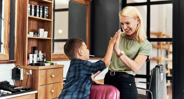 Good hair puts everyone in a good mood. an adorable little boy giving his hairdresser a high five inside a salon