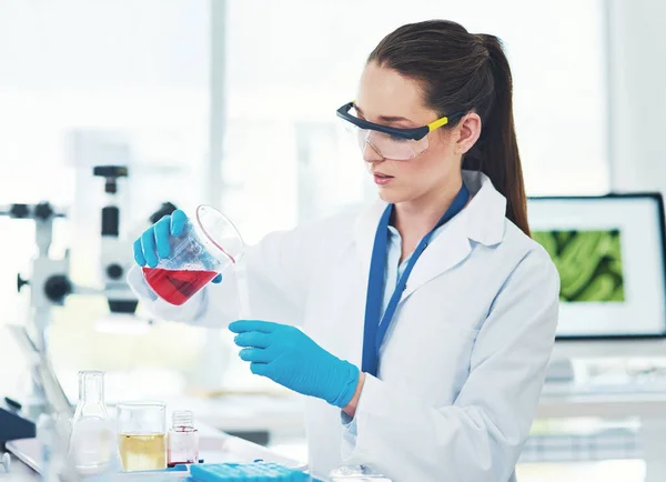 I hope this works. a focused young female scientist mixing chemicals together inside of a laboratory during the day