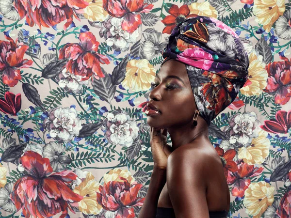 Floral on floral. Studio shot of a beautiful young woman wearing a traditional African head wrap against a floral background