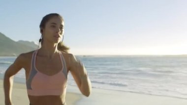 Plaj, koşu ve spor yapmak için okyanusun kıyısında bir kadın. Koşucu sağlığı için egzersiz. Spor, maraton antrenmanı ve deniz kenarındaki bir sporcunun kardiyo enerjisi açık havada sabah koşusu..