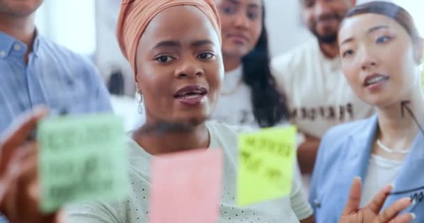 オフィスでガラスの壁に取り組んでビジネスミーティング 創造的な計画やデザイナーのための黒の女性 リーダーと付箋 リーダーシップ チームコラボレーション アフリカの女性トレーニングデザイン従業員 — ストック動画