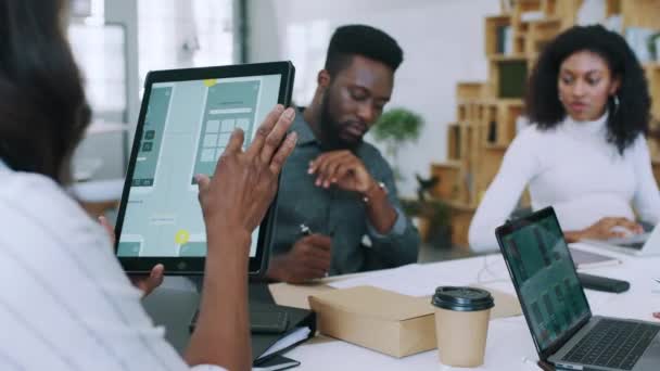 フィードバック レビュー プロジェクト開発のためのタブレットと電話 デザイナーミーティング 黒の人々 技術とプロのアプリケーション設計チームは 画面と一緒にブレインストーミング — ストック動画