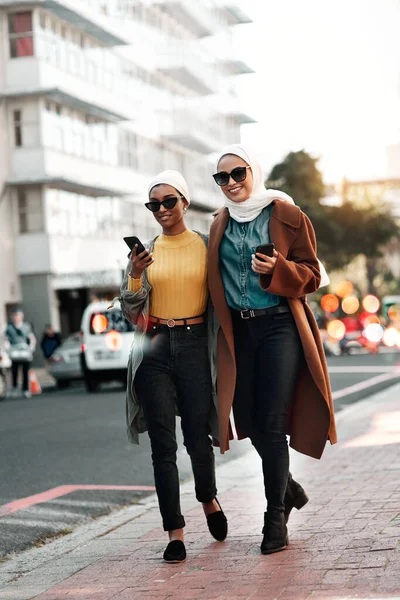 Travelling is worth more than money ever will. Full length shot of two young attractive women wearing sunglasses and headscarves while walking through the city