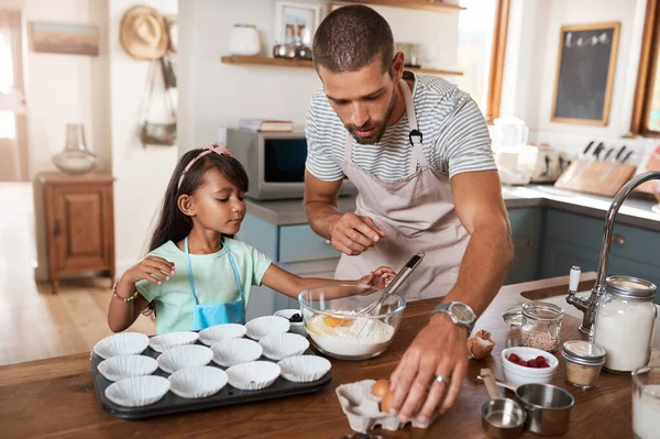 We have everything we need for some delicious cupcakes. a young man baking at home with his young daughter