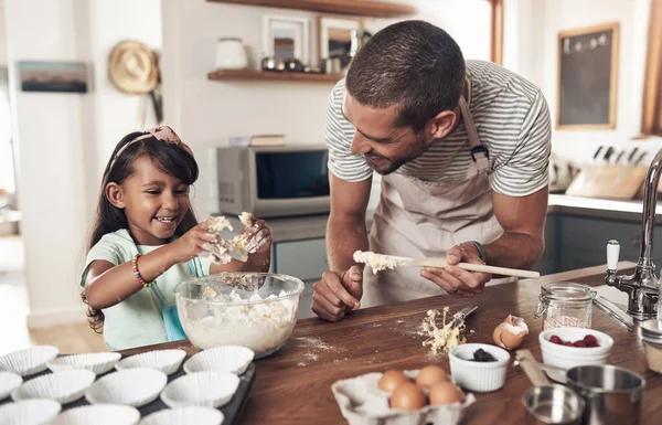 Families are like fudge mostly sweet, with a few nuts. a father teaching his daughter how to bake in the kitchen at home