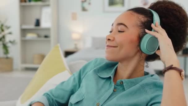 音乐和黑人妇女与耳机在沙发上的健康休息和流淌与满意的微笑 在家里卧室里听音乐音频应用程序的女孩自顾不暇 快乐而舒适 — 图库视频影像