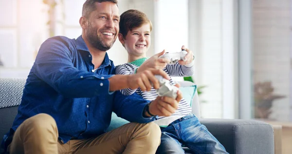 Competitiveness runs in the family. a cheerful father and son playing video games together while sitting on a couch at home