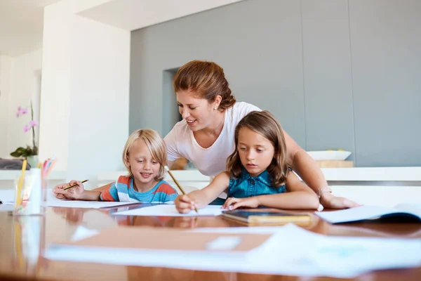 Make your home a happy learning environment. a young mother helping her two small children with their homework at home