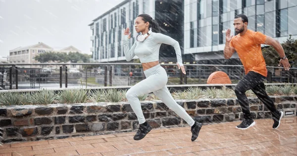 Running, fitness and couple in the rain with runner energy, speed and fast people doing sport. City, exercise and workout sports in winter doing cardio for a marathon or race athlete training.