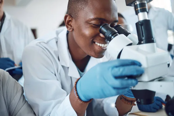 Science, microscope and students learning in class, classroom physics and happy with research in a lab. Innovation, scientist and African teenager in high school studying microbiology for education.