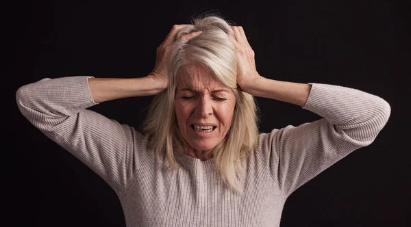 Senior woman, stress or anxiety on black background in studio in schizophrenia, bipolar disorder or psychology burnout. Retirement elderly, anxiety or mental health headache with fear, pain or crisis.