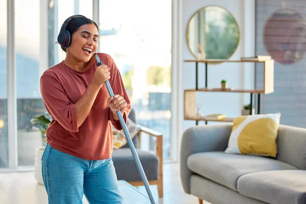Singing, cleaning and headphones of a woman with music working in a home dancing with happiness. Spring cleaning, cleaner and happy person sing and dance with a mop in living room listening to audio.