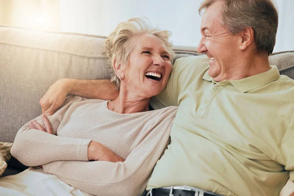 上了年纪的夫妻 笑着抱在沙发上 在快乐的关系中 傻笑着或在家里粘合在一起 上了年纪的夫妻在客厅沙发上鬼鬼祟祟地笑着 幽默着或放松着 — 图库照片