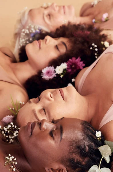 Sleeping, relax and face of women with flowers for peace, skincare and natural makeup against a studio background. Floral, sleep and diversity with model people, flower crown and calm beauty.