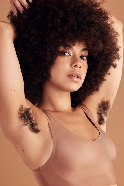 Armpit hair, body positivity and portrait of a black woman in studio on a brown background for natural care. Health, wellness and empowerment with an attractive young afro female showing her underarm.