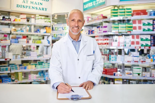 Tell me your symptoms and Ill find a guaranteed solution. Portrait of a mature pharmacist writing on a clipboard in a chemist