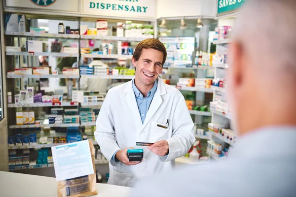 Happy to be of service. a handsome young male pharmacist helping a customer in the pharmacy