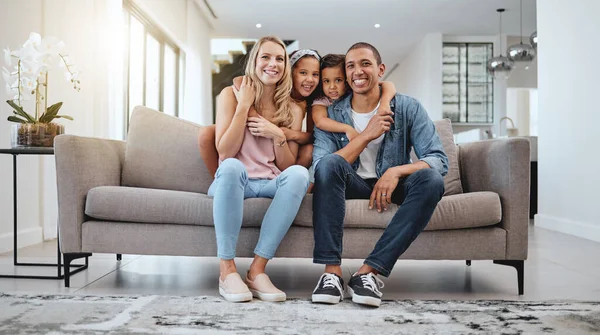 Happy family, living room and portrait of a mother, dad and girl children smile on a home sofa. Relax, hug and parent care of a mom, father and kids in a interracial family house with love.