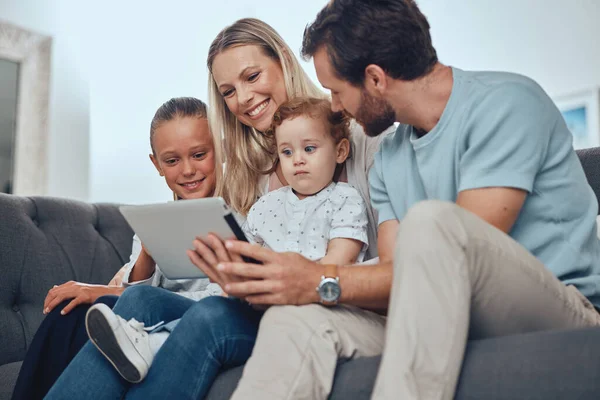 Happy family, tablet and relax sofa in living room together for quality time, bonding and streaming video online. Parents, children smile and watching on digital tech device on couch in family home.