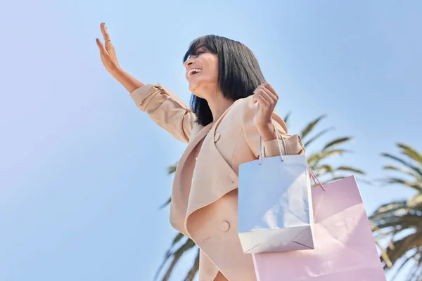Sky, bag and woman wave after shopping for retail fashion deal, discount sales product or luxury designer clothes. Hawaii palm trees, market choice and customer with gift from mall store bottom view.