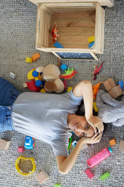 Stress, mother or toys in messy living room for spring cleaning, housekeeping or tidy maintenance in top view. Anxiety, mental health or burnout mom and children play objects in Brazilian family home.