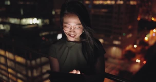 デジタルタブレットや屋上の夜市内のソーシャルメディア 研究や都市の背景にネットワーキングのために ニューヨークで遅く働いている起業家によるビジネス女性 バルコニー オンライン検索 — ストック動画