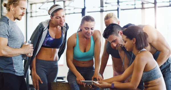 Good health is always trending. a group of happy young women using a digital tablet together in a gym