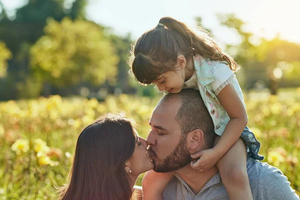 Family goals. an adorable little girl watching her parents kiss during a family bonding session in the park