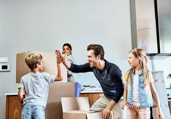 Give me a high five buddy. an affectionate young father giving a high five to his son while unpacking boxes in their new home