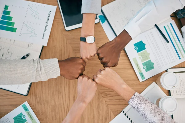 Diversity, fist hands and teamwork with documents on table for marketing business meeting, creative collaboration and goals support motivation. Team, circle hand and planning strategy or logistics.