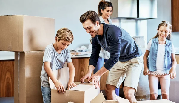 And they lived happily ever after. a cheerful young family of four working together to unpack boxes in their new home on moving day